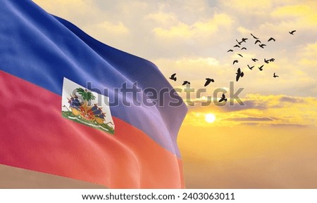 Waving flag of Haiti against the background of a sunset or sunrise. Haiti flag for Independence Day. The symbol of the state on wavy fabric. Royalty-Free Stock Photo #2403063011