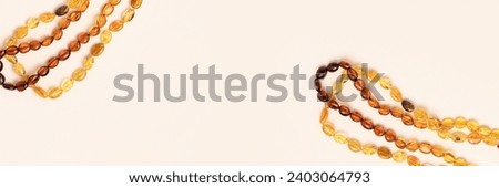 Banner with amber beads on a beige background. Copy space for text.