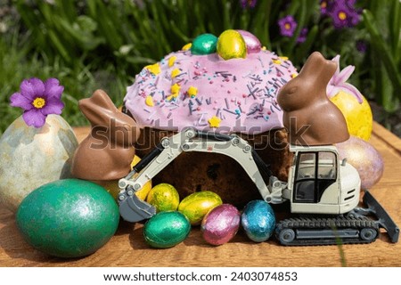 model of a toy excavator, Easter cake, chocolate bunnies with bright multi-colored eggs. Easter spring holiday concept, greeting card from construction companies