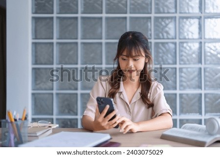 Young asian student in casual clothes watching tutorial and studying lecturer education online class with smartphone digital technology while reading knowledge data and working homework in university.