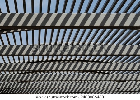 Abstract psychedelic pattern of shadow and light formed on a cement arch overhang.