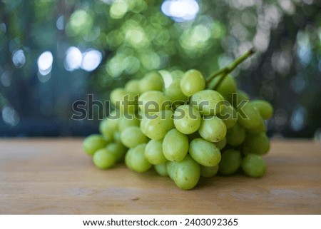Bunch of ripe and juicy green grapes on wood table