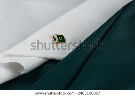 Pakistan independence day small metal Pakistan flag laying on white and green fabric 