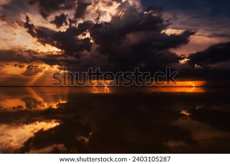 Thunderous dark sky. Black clouds and thunderstorm lightning. Concept on the theme stormy, thunderbolt, thunder, rain. Dramatic skies over the water landscape. Nature background.