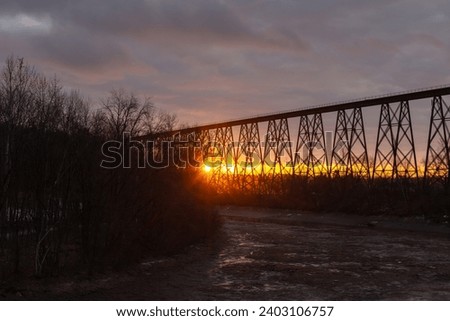 View of the 1908 railway trestle bridge over the Cap-Rouge River seen during a partly cloudy dark winter sunrise, Cap-Rouge area, Quebec City, Quebec, Canada Royalty-Free Stock Photo #2403106757