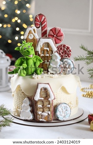 Homemade cake decorated with green dragon mastic figurine and gingerbread on the white background.