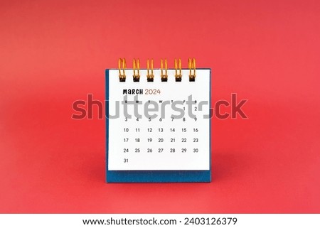 March 2024 white desk calendar on red color background.
