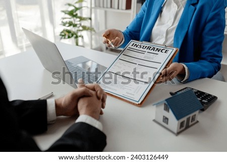 House insurance paperwork, A realtor is explaining home insurance documents to a buyer in his office at the company, Sign home insurance documents, make an agreement together. Royalty-Free Stock Photo #2403126449