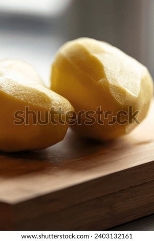 Two Peeled Potatoes on Wooden Board Close-Up 