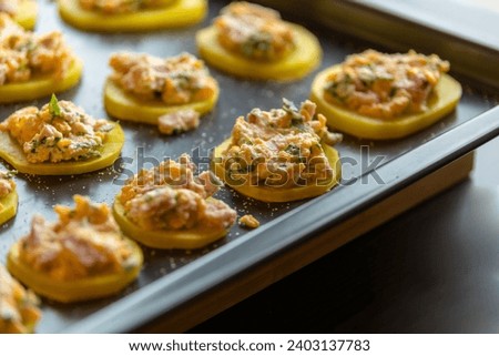 cut raw potatoes adorned with delicious stuffing, arranged in a tray and ready to cook