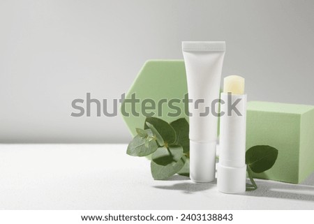 Stylish presentation of different lip balms on white table, space for text Royalty-Free Stock Photo #2403138843