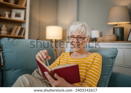 One woman mature senior caucasian female pensioner modern grandmother read book at home wear eyeglasses real person copy space Royalty-Free Stock Photo #2403142617