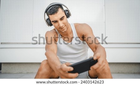 Portrait of young man outdoor use headphones and smart phone to play video games