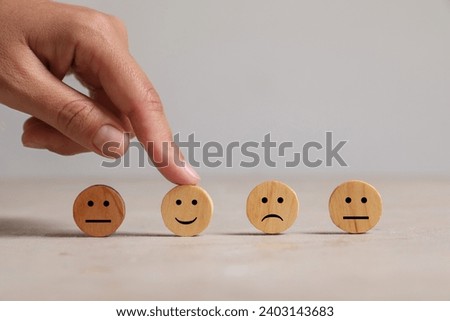 Choice concept. Woman choosing wooden circle with happy emoticon among others at light table, closeup