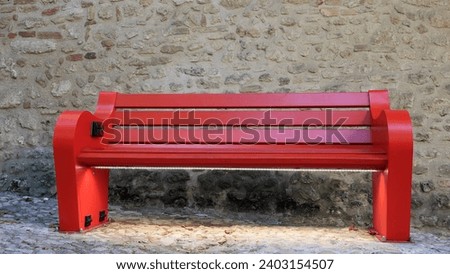 Red smart bench with LED light and USB connection. Stone wall Royalty-Free Stock Photo #2403154507