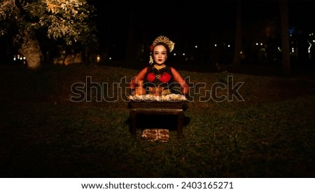 a female dancer looks focused on her ritual with a peaceful facial expression in front of offerings that look fresh and lively at night