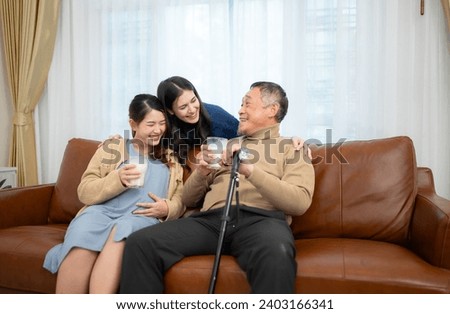 A happy family sits on the sofa in the living room, Father and daughter are pregnant drinking milk and talk to each other. Royalty-Free Stock Photo #2403166341