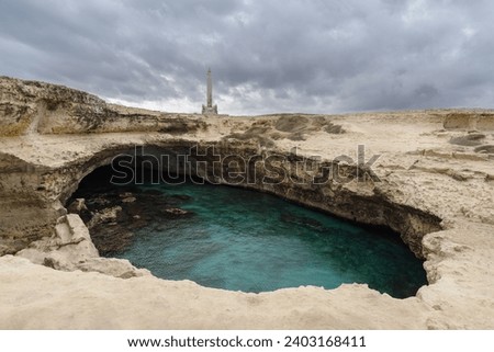Poetry Cave (Grotta della Poesia) natural pool surrounded by rugged limestone cliffs. It's one of the most well known natural rock formations in the world inside the archaeological site. Apulia, Italy Royalty-Free Stock Photo #2403168411