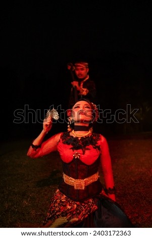 a female dancer in a red costume sat in the silence of the night which strengthened the sadness in the middle of the field