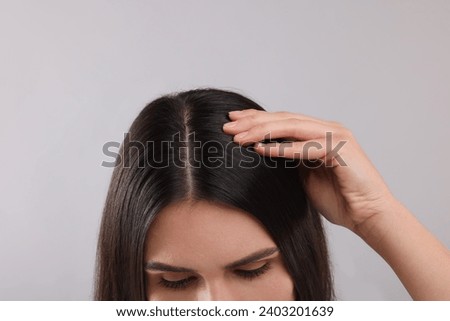 Woman examining her hair and scalp on grey background, closeup Royalty-Free Stock Photo #2403201639