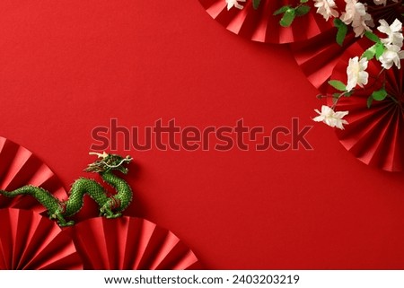 Lunar New Year background. Chinese dragon, folding paper fans, sakura on red background. Flat lay, top view. Royalty-Free Stock Photo #2403203219