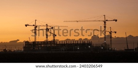 Silhouette of a building with backlit orange sky during sunset.
