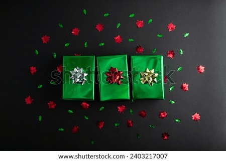 wrapped green gift box with colored ribbon as a present for Christmas, new year, mother's day, anniversary, birthday, party, on black background, top view. Present for a colleague at work.
