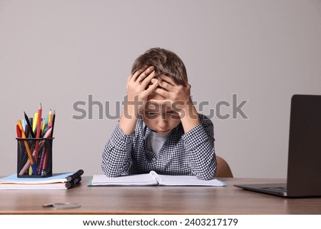 Little boy with stationery suffering from dyslexia at wooden table Royalty-Free Stock Photo #2403217179