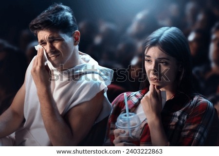 Young man and woman visiting cinema, watching sad movie, drama film. Sitting and crying. Sad moment. Concept of leisure time, relationship, emotions, weekend activity Royalty-Free Stock Photo #2403222863