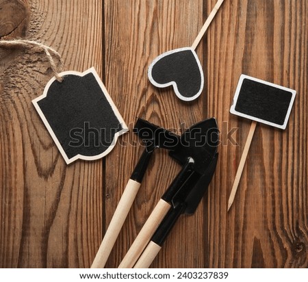 Chalkboard labels, blank wooden blackboard tags, garden tools and sign on wooden background
