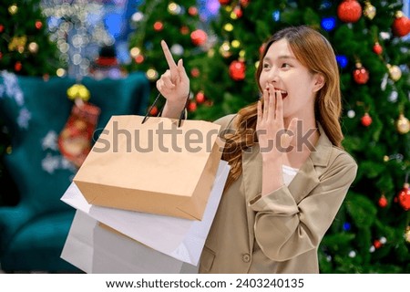 Beautiful asian girl hold shopping bags on Christmas tree bokeh light background at night, happy new year vibes concept