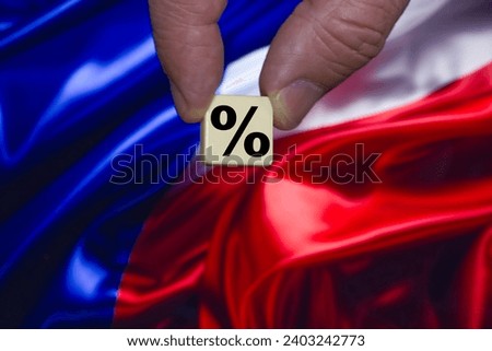 Fingers holding a single block with a black percent sign on the background of the Russia flag.