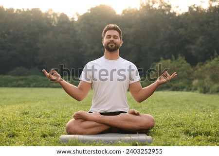 Man practicing yoga on mat outdoors. Lotus pose