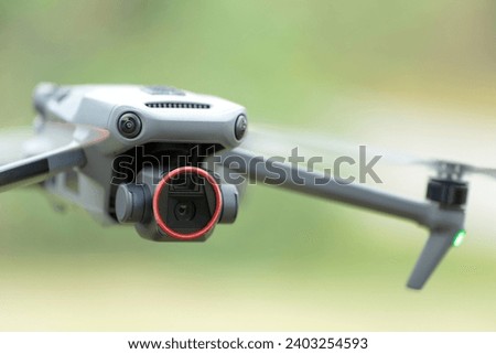 Drone with digital camera and fast rotating propellers flying taking video and pictures