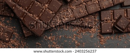 Tasty chocolate bars and shavings on dark grey table, flat lay. Banner design Royalty-Free Stock Photo #2403256237