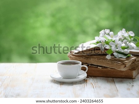 tea cup, old books and apple flowers on wooden table in garden. tea party. spring season. atmosphere gentle romantic image. copy space