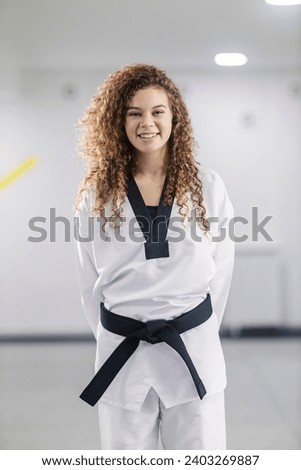 Portrait of a taekwondo sportswoman with black belt standing at martial art school.
