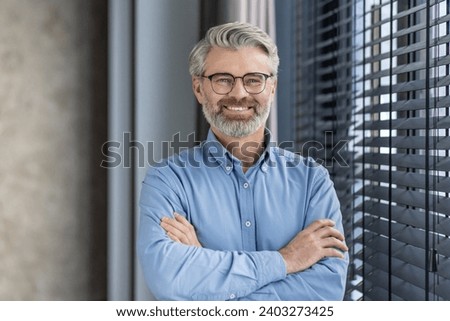 Portrait of mature successful businessman boss, senior gray-haired man inside office smiling looking at camera with crossed arms, experienced financier banker accountant in shirt.