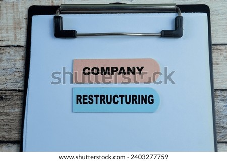 Concept of Company Restructuring write on sticky notes isolated on Wooden Table.