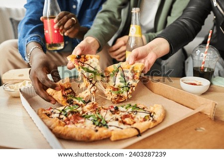 Close up shot of diverse friends hands picking up slices of appetizing pizza with sauce and stretched cheese Royalty-Free Stock Photo #2403287239
