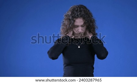Stressed young woman rubbing neck trying to appease mental anguish while standing on blue background Royalty-Free Stock Photo #2403287965
