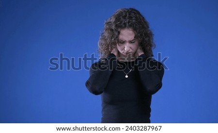 Stressed young woman rubbing neck trying to appease mental anguish while standing on blue background Royalty-Free Stock Photo #2403287967