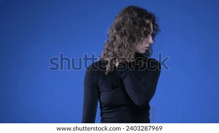 Stressed young woman rubbing neck trying to appease mental anguish while standing on blue background Royalty-Free Stock Photo #2403287969