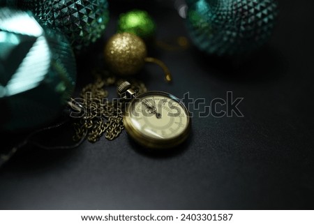 Happy 2024 concept, clock with Christmas ball on black paper background.
