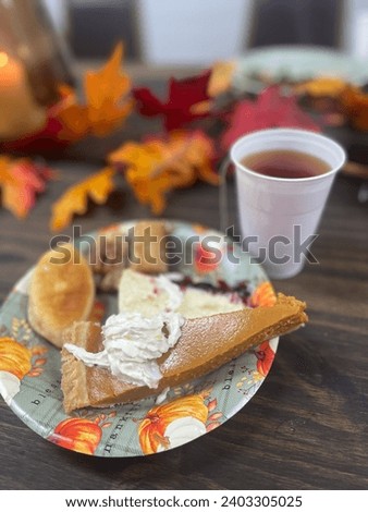 Thanksgiving dinner. Beautiful table with thanksgiving autumn decoration and bright leaves. Cup of tea and food on the table. Pumpkin pie with cream on a plate. Closeup picture. Holiday concept