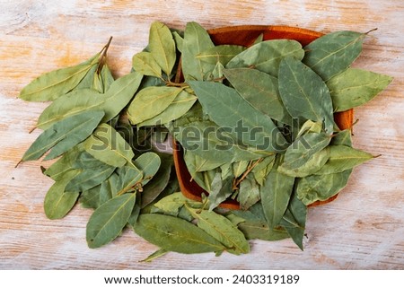 Pile of dried green bay leaves lie on wooden table Royalty-Free Stock Photo #2403319189