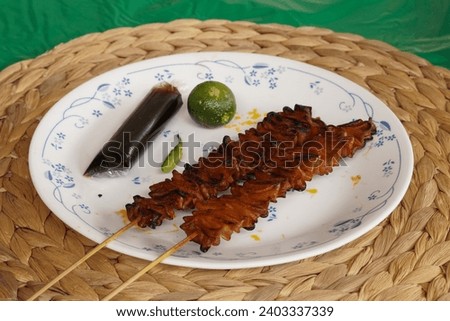 Filipino food Isaw ng Manok BBQ or grilled chicken intestine with soy sauce and kalamansi fruit for dip 
