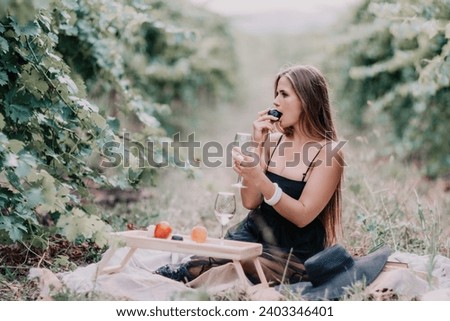 Woman picnic vineyard. Happy woman with a glass of wine at a picnic in the vineyard, wine tasting at sunset and open nature in the summer. Romantic dinner, fruit and wine.