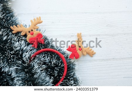 Christmas decoration frame from decorated green fir branches of a Christmas tree and 
cute cartoon reindeer a on white wooden table backdrop. Empty place for inspirational wishes text .  Banner backdr