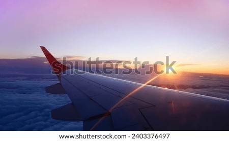The sunset scene with Scenic View of the Wings of a aero plane flying above the clouds. Travelling by aero plane  Royalty-Free Stock Photo #2403376497